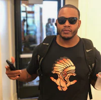 a man wearing sunglasses and a t - shirt holding a cell phone